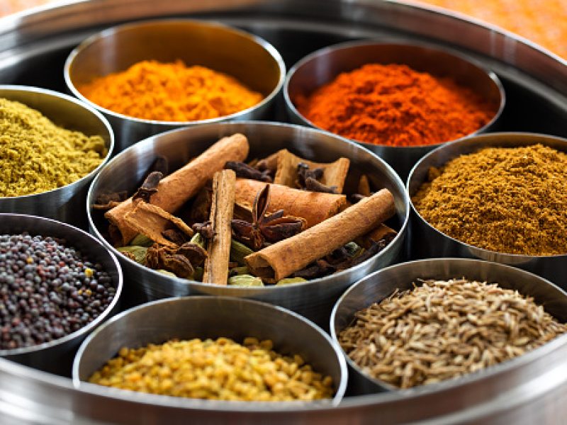 Whole and ground spices neatly organized in a metal tin.